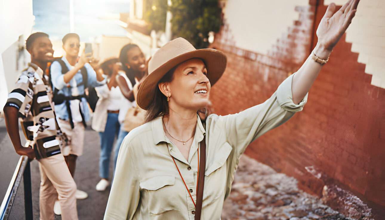 Image: A smiling tour guide standing in front of a historical monument, gesturing towards it. The guide holds a map, adding a touch of expertise to the travel experience. The backdrop features a blend of architectural marvels and natural beauty, promising a rich and immersive exploration. #ExpertGuide #CulturalExploration